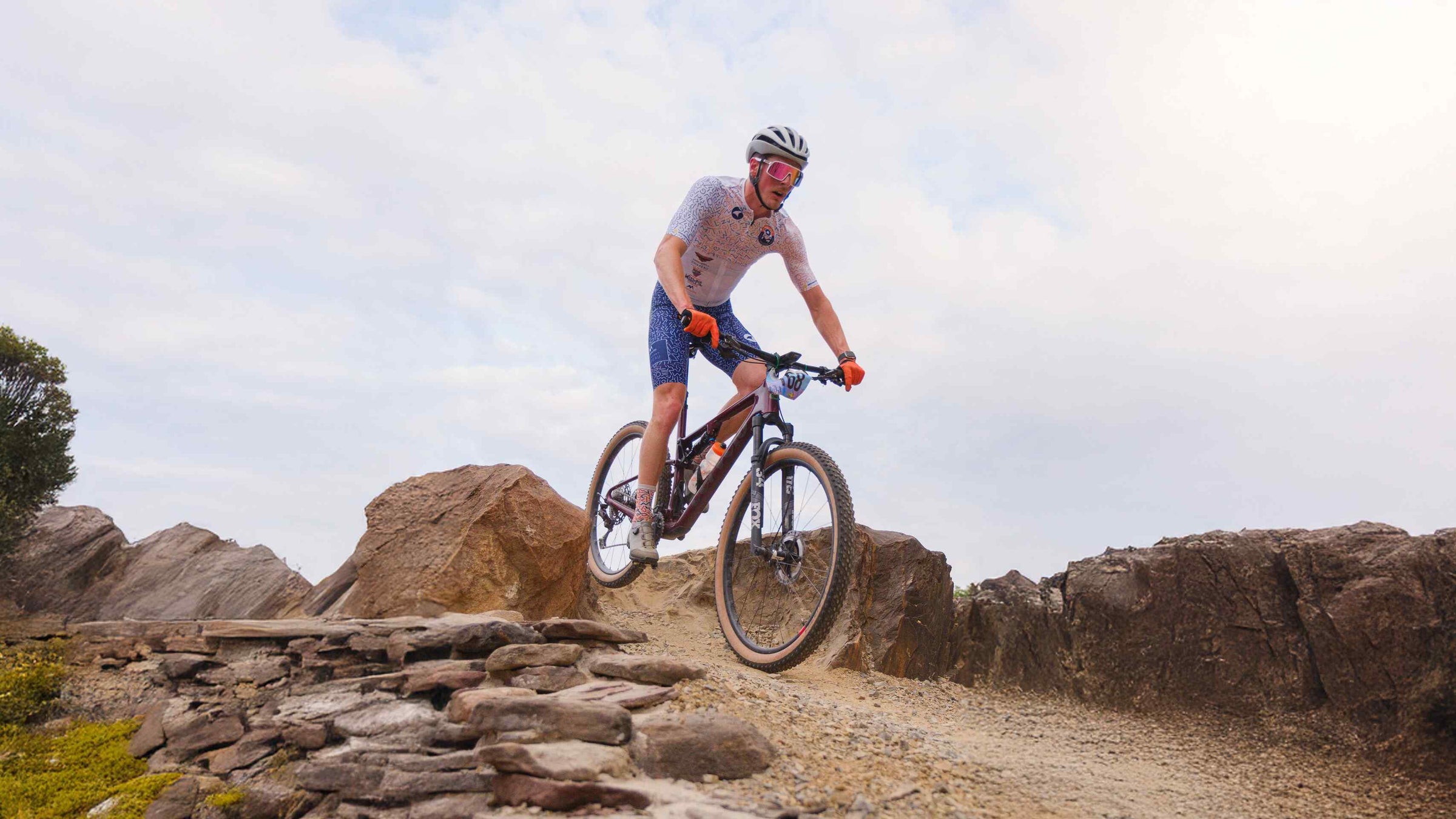 Cyclist wearing Cumberland Valley Collective team cycling kit made by Pactimo hopping some rocks on a mountain bike