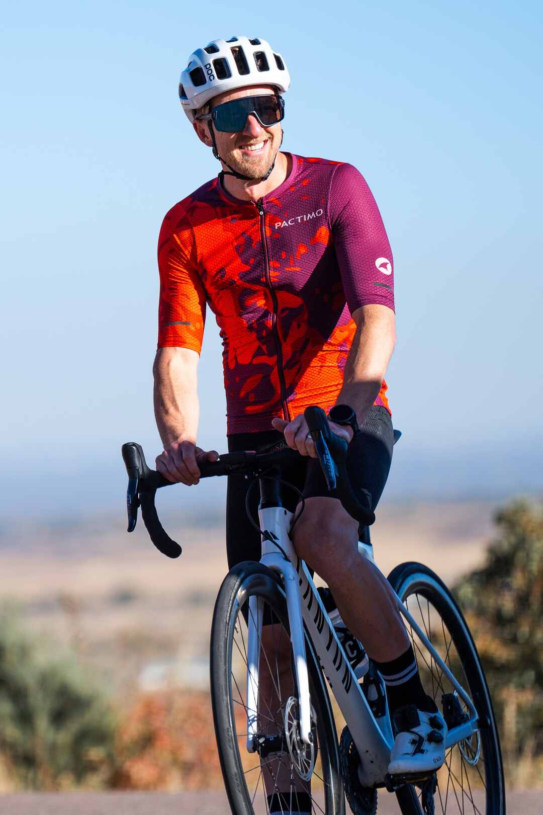 Male cyclist wearing a bright and colorful orange and purple mesh cycling jersey