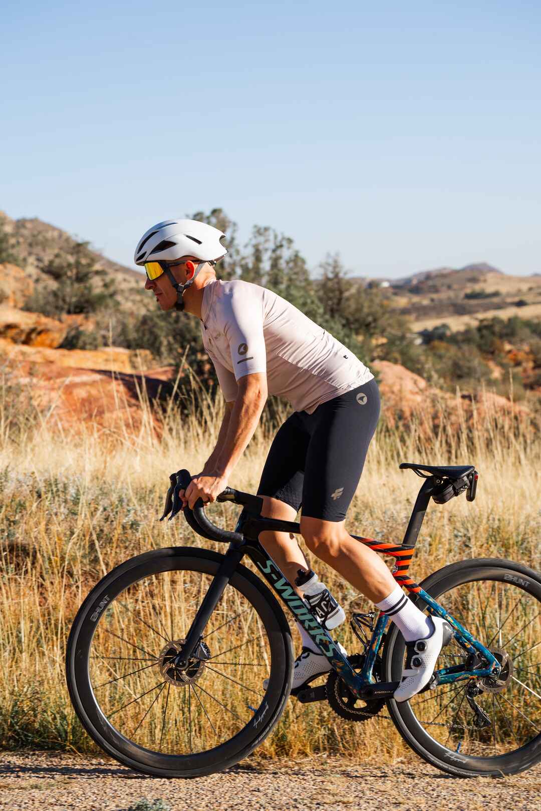 Male cyclist wearing black cycling bib shorts and a sand colored cycling jersey