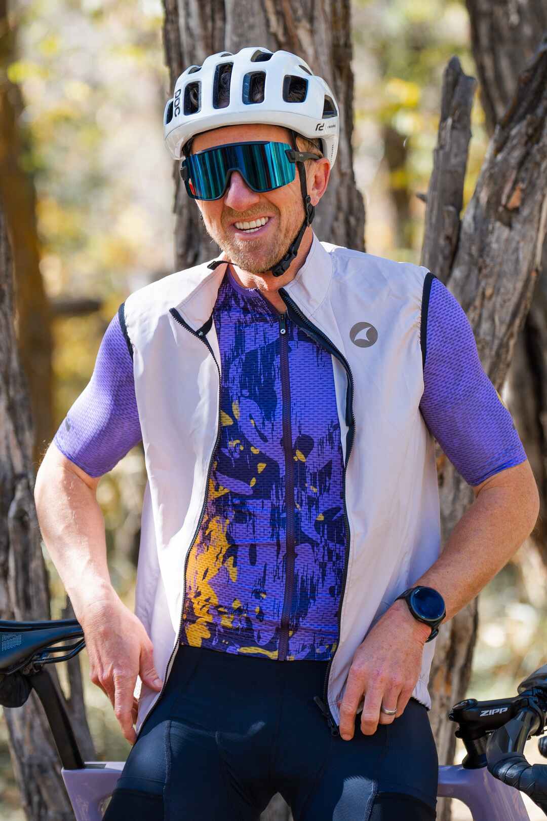 Male Cyclist wearing purple mesh cycling jersey and white cycling wind vest.