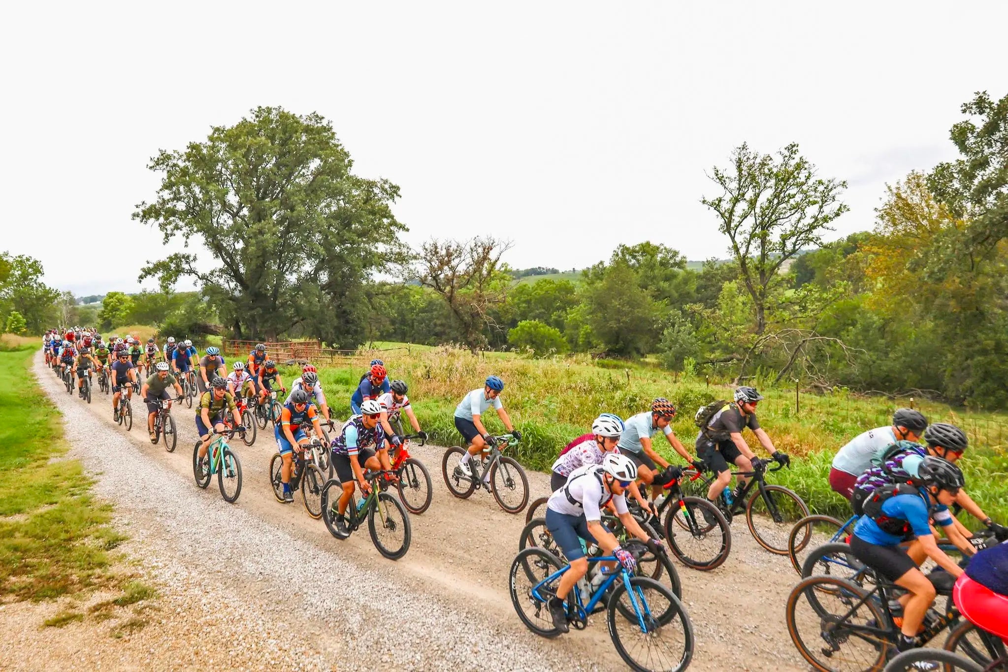 a larger group of cyclists riding on a gravel road