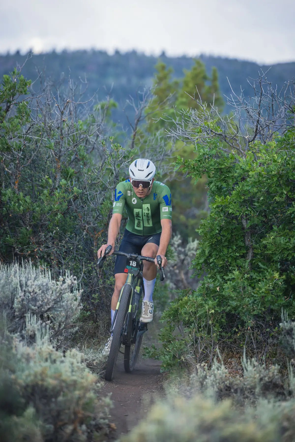 Sam Brown in his Pactimo custom team kit riding through a narrow dirt path