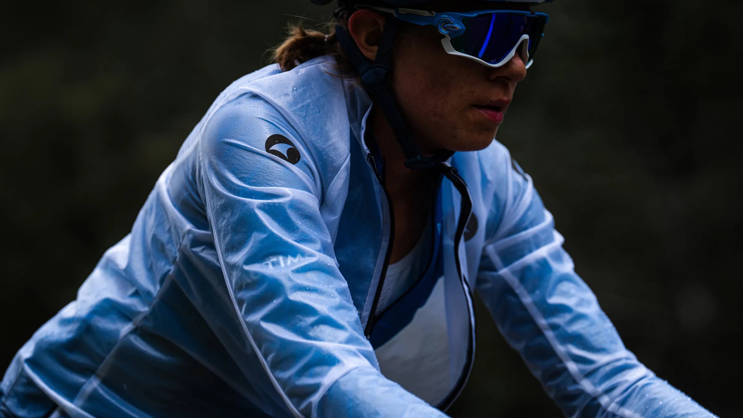 A female cyclist wearing the Pactimo Ultra-Lite Rain Jacket in the rain