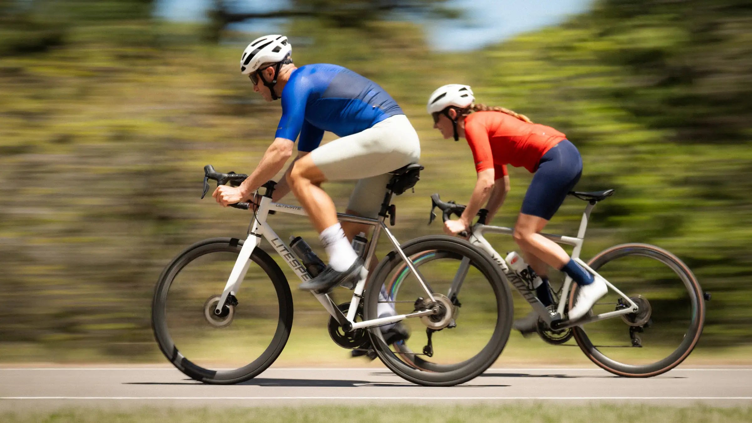 Male and female cyclists in colorful cycling kits riding fast on the road