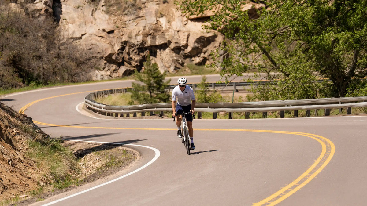 Person cycling on a winding road with natural scenery