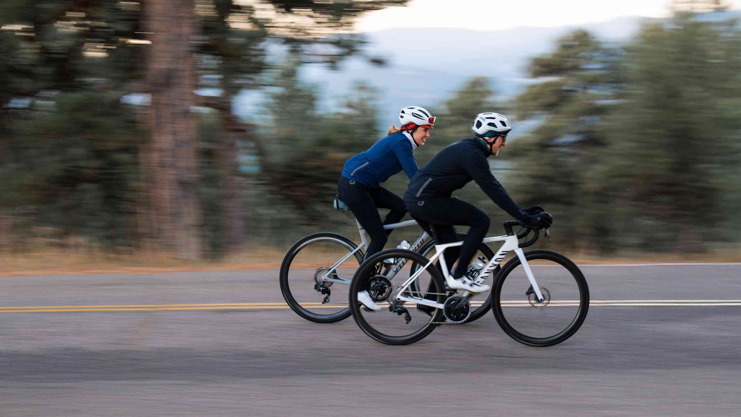 Two cyclists wearing jackets and tights riding on the road