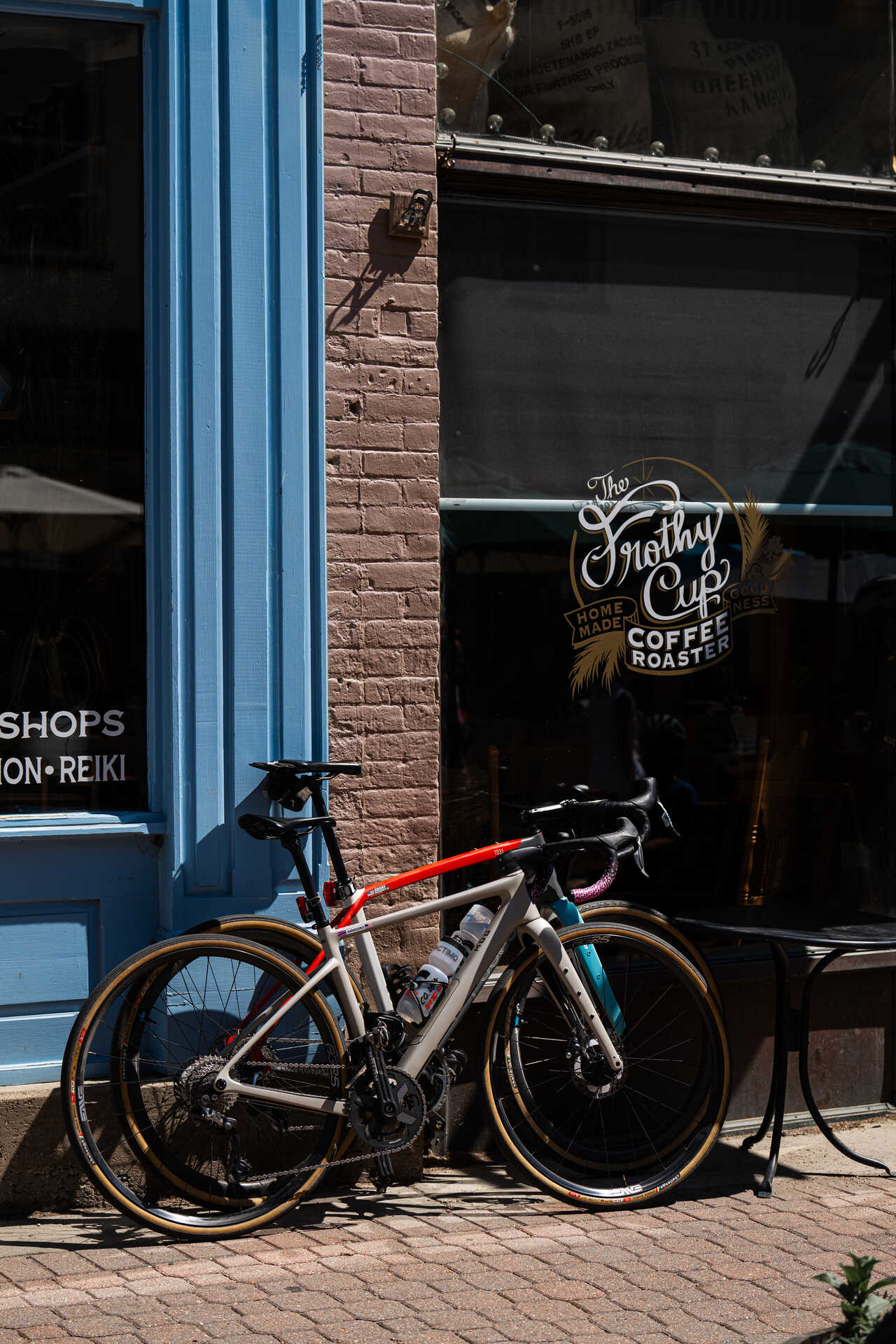 Two road bikes leaned against the exterior of The Frothy Cup coffee roaster, their riders inside or nearby after a ride