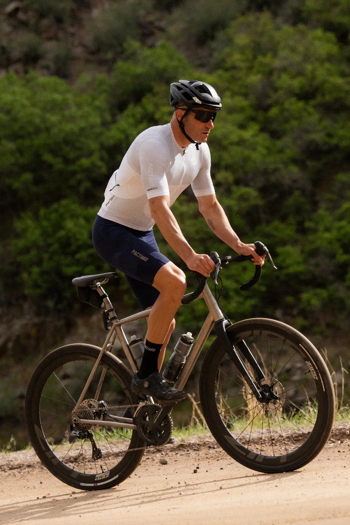 a male cyclist in a white and blue cycling kit on a dirt road