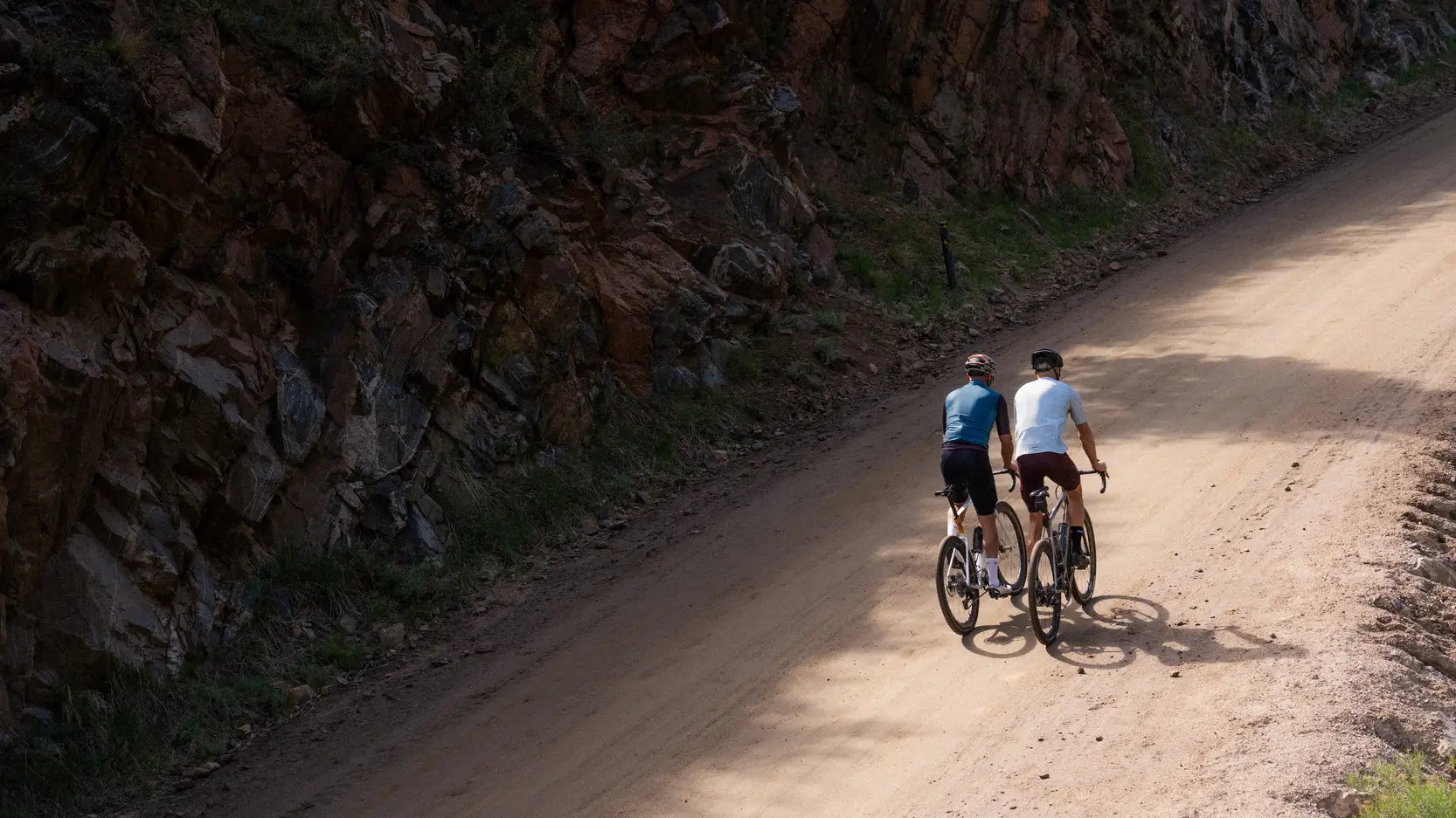 Two cyclists riding on a dirt road 