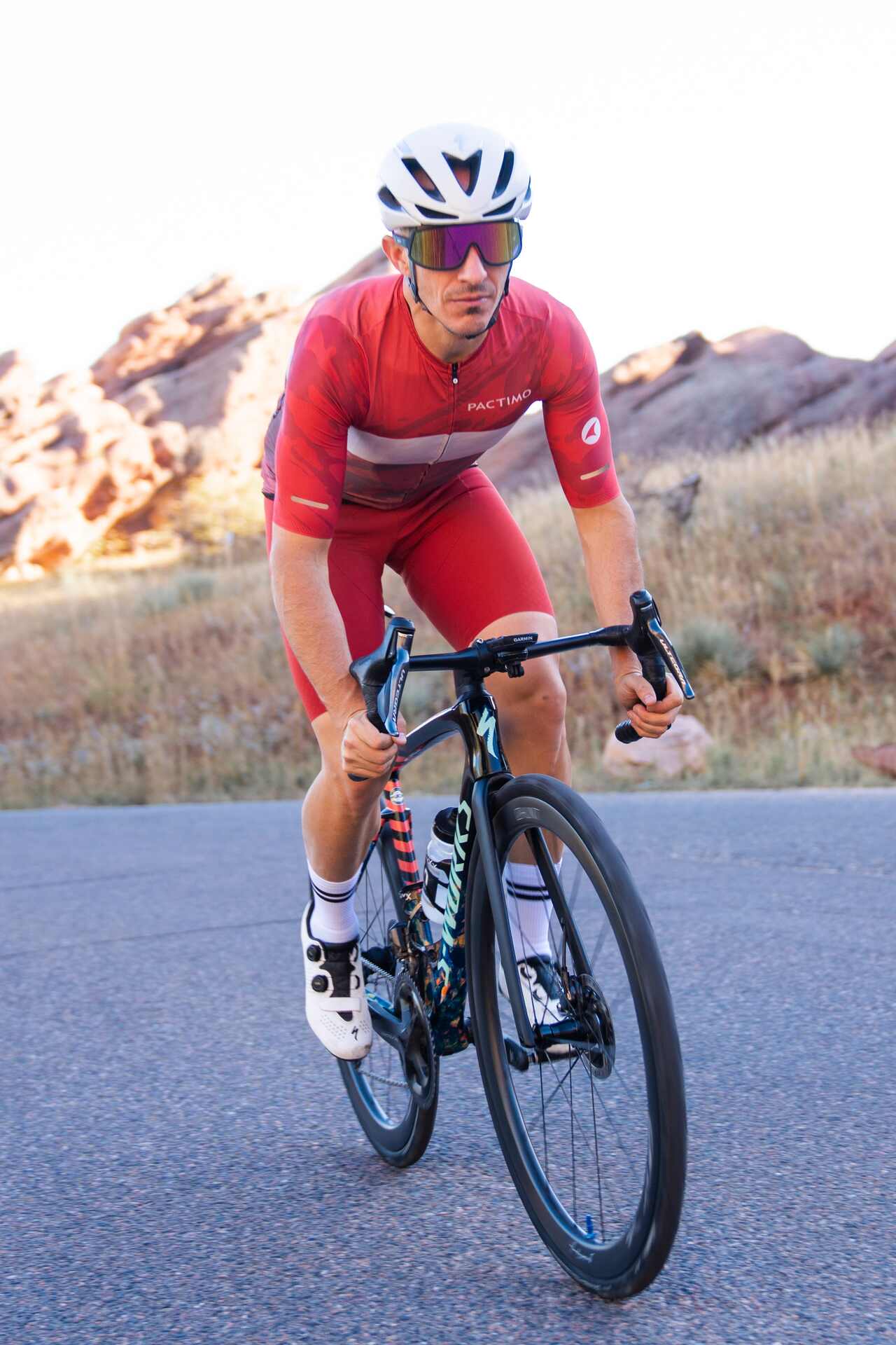 Cyclist in red Flyte Bibs riding a bicycle on a road with desert landscape in the background