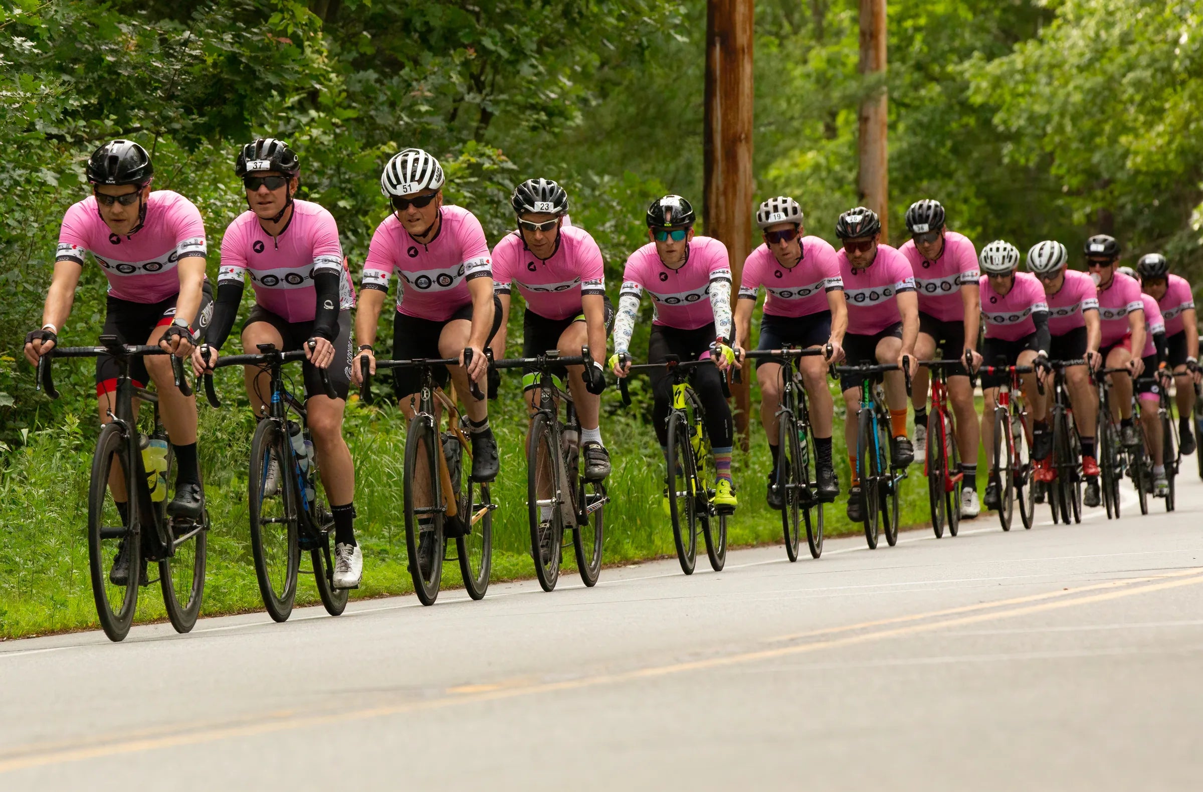 a long line of cyclists in matching jerseys riding in a paceline