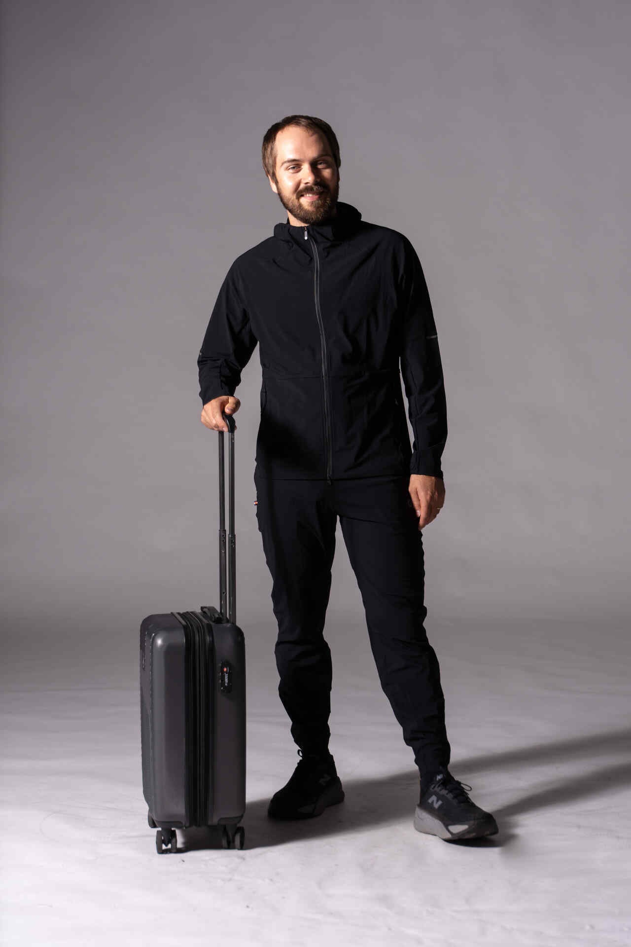 Man wearing Pactimo Prologue Jacket and Jogger with a black suitcase